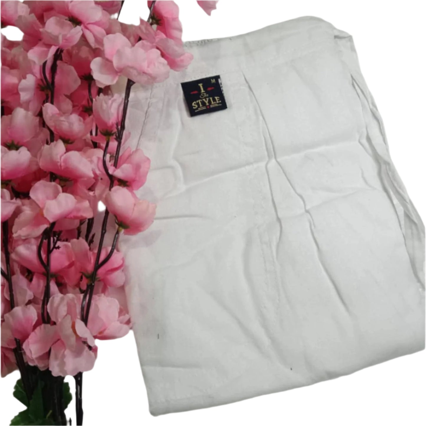 White quilt with a brand label next to pink flowers on a white background