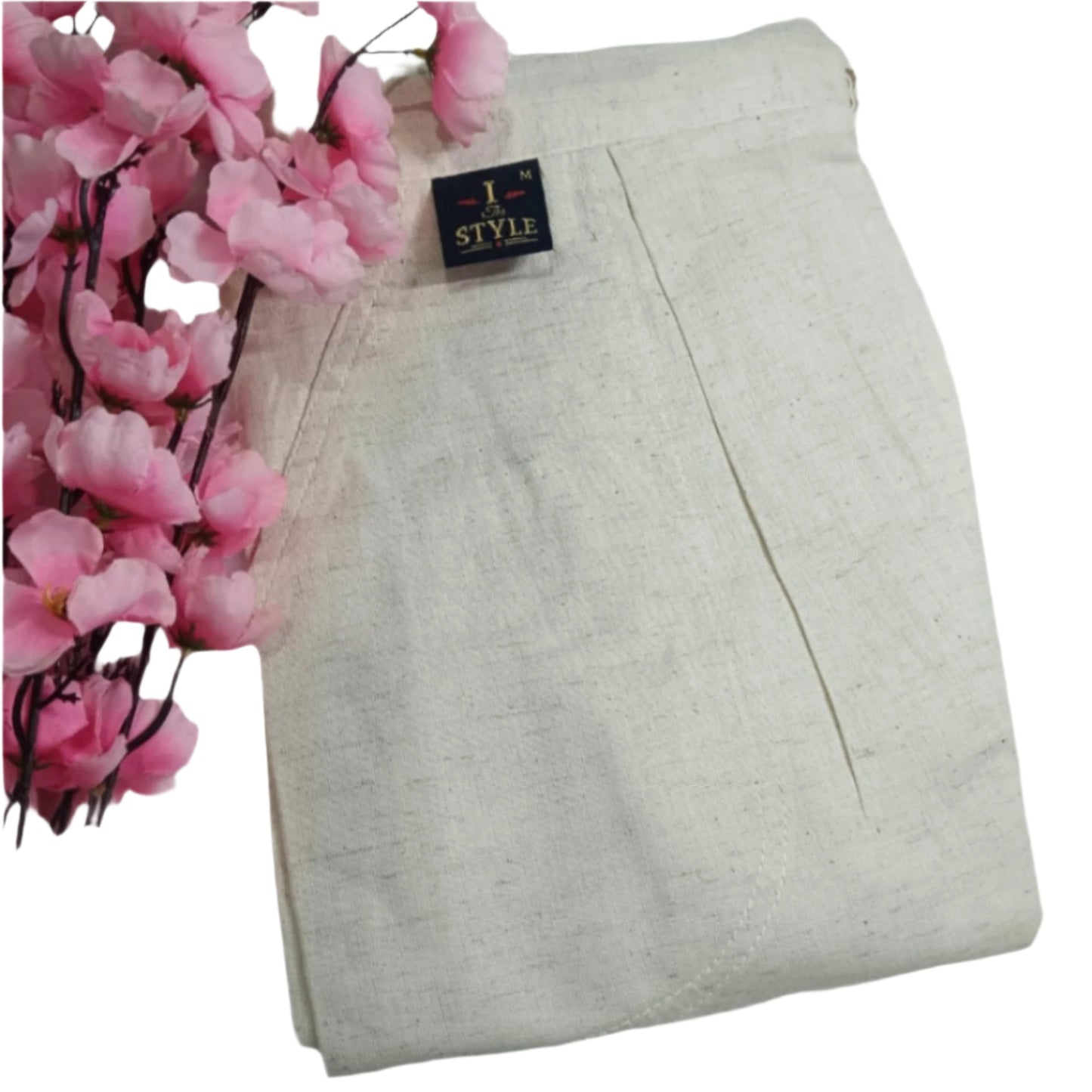 Light gray pants with a tag on a white background, next to pink artificial flowers.