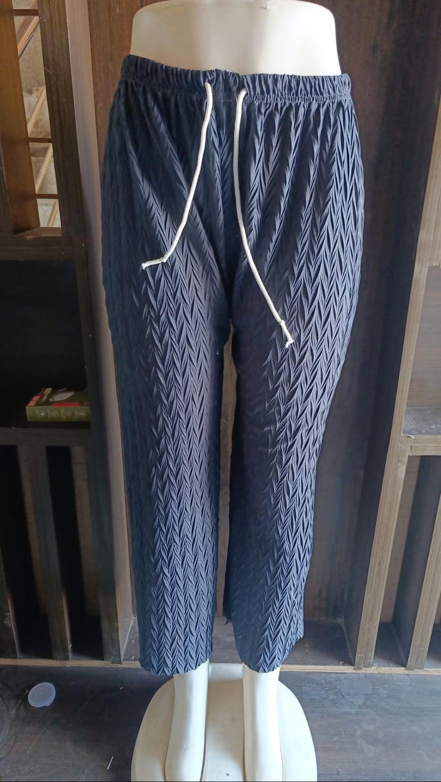 Blue knitted pants with a white drawstring on a mannequin against a white background