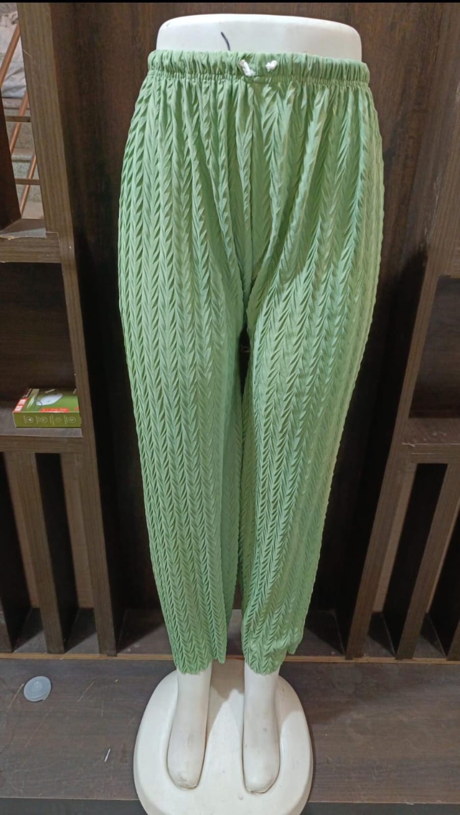 Green knitted pants on a mannequin against a white background