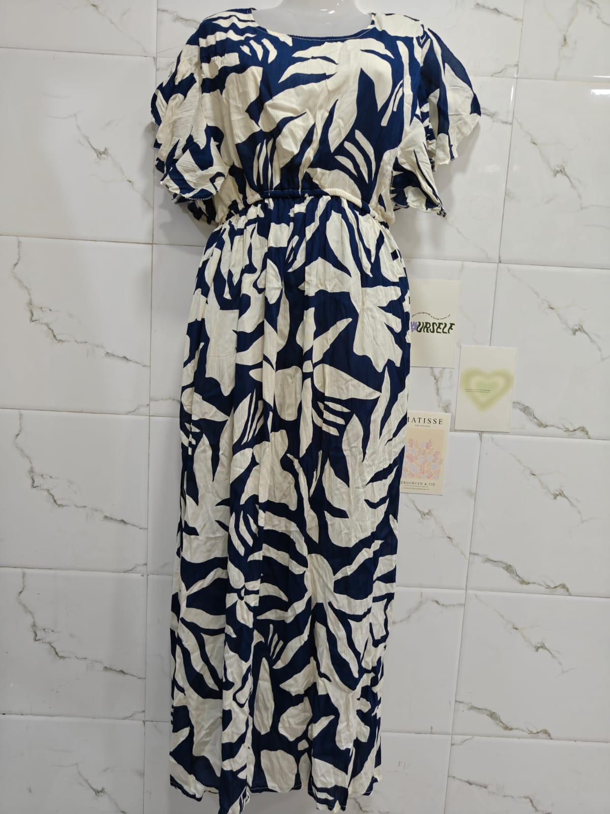 Blue and white floral dress on a marble background with a visible tag.