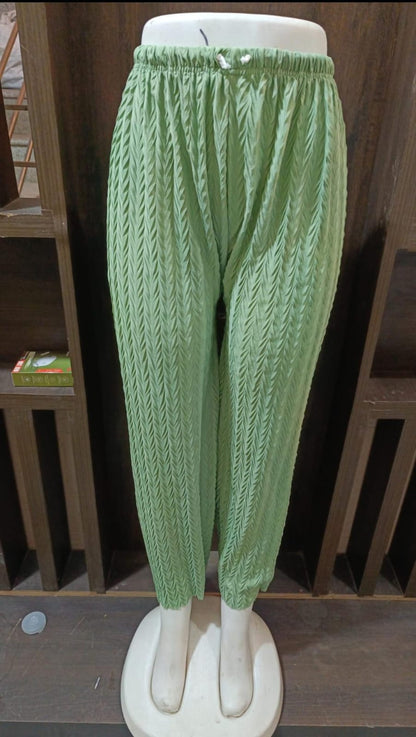 Green knitted pants on a mannequin against a white background