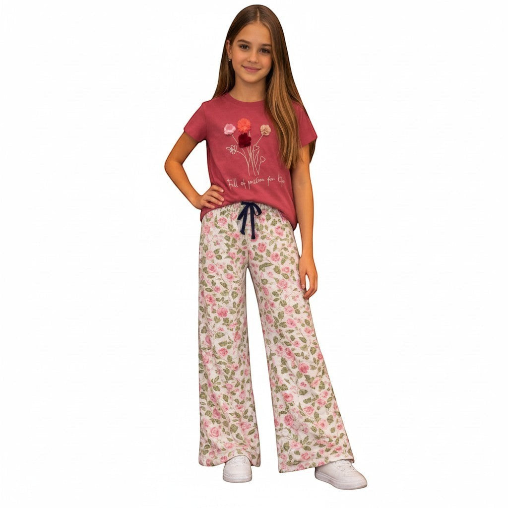 For She - Avalukaaga girl wearing pink floral wide leg pajama pants with drawstring waist and matching t-shirt.